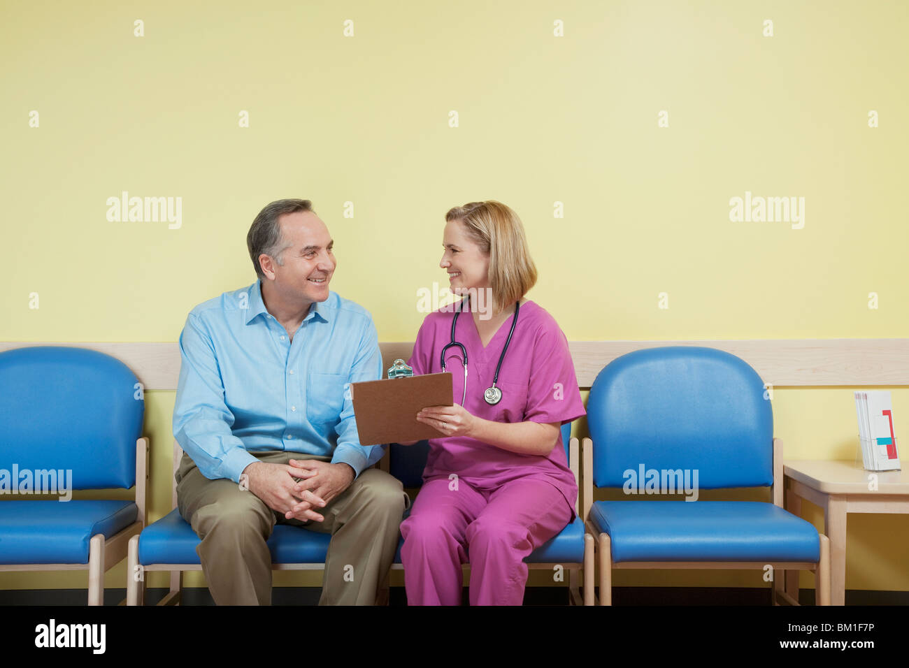 Female nurse talking to a patient in the waiting room Stock Photo - Alamy