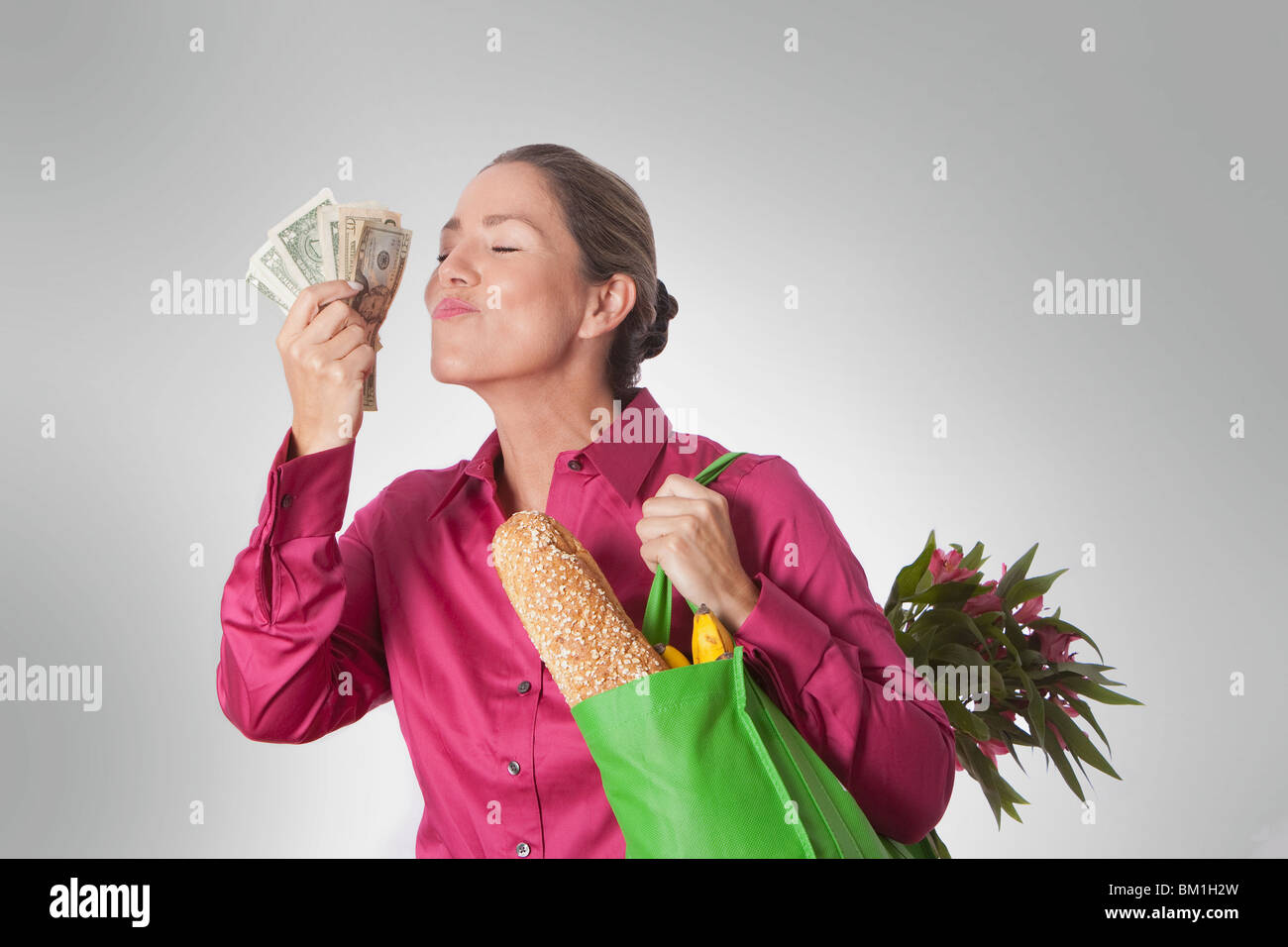 Woman holding a shopping bag of groceries and currency notes Stock Photo