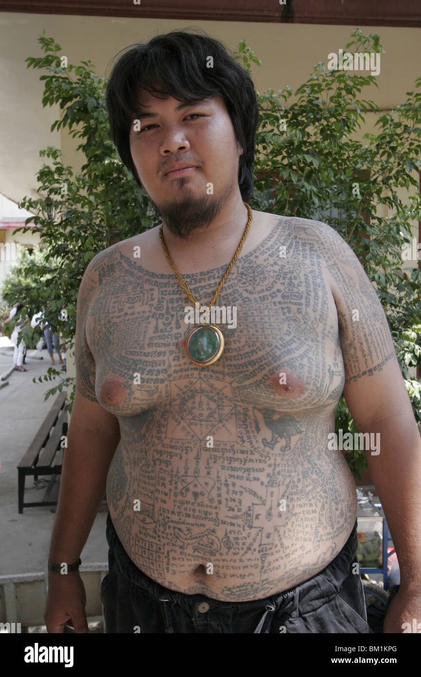 A fat young man shows off his tattoos during Wai Kru Day at Wat Bang Phra, a Thai temple where monks tattoo their devotees. Stock Photo