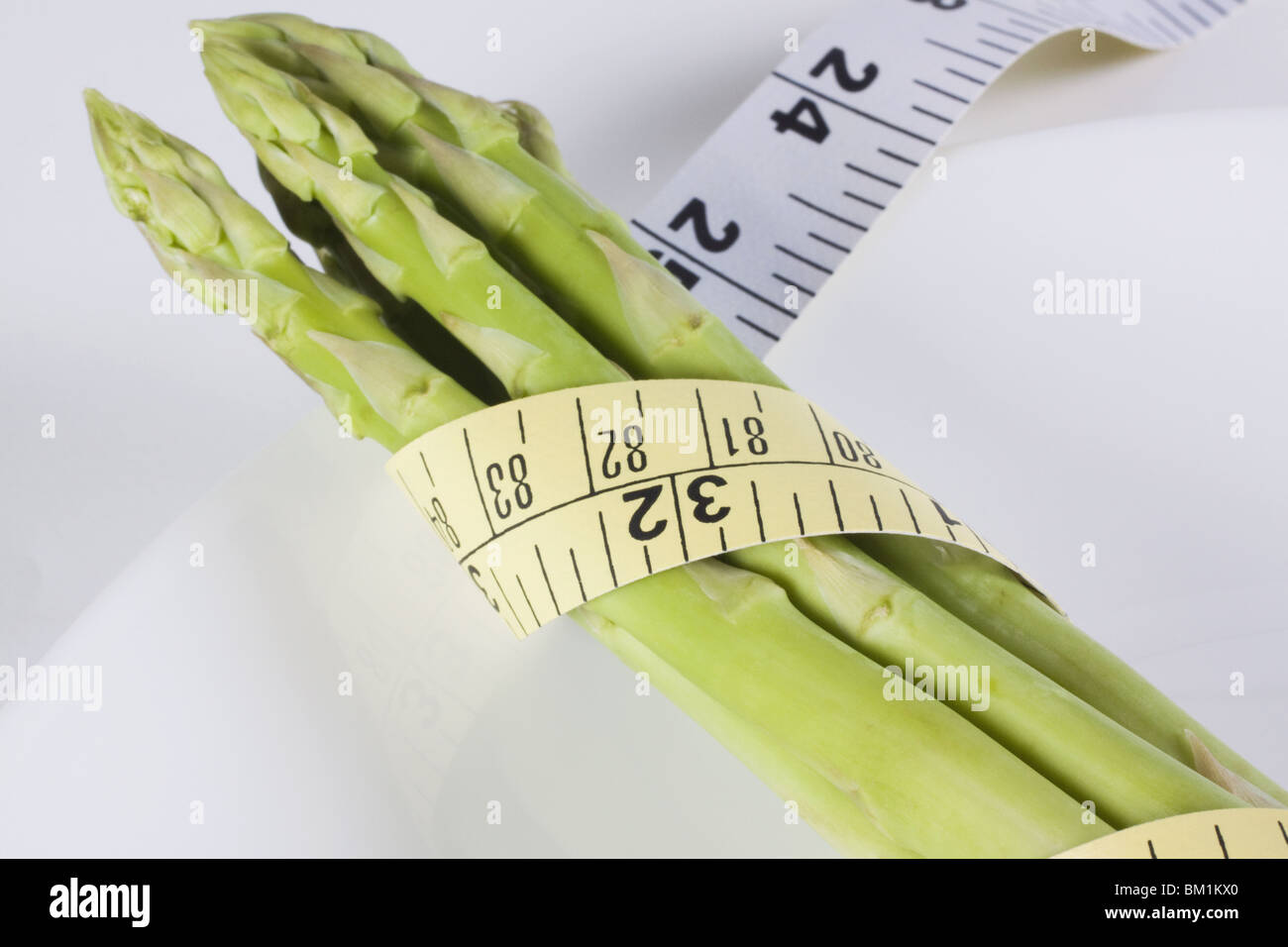 Close-up of a tape measure wrapped around asparagus stalks Stock Photo