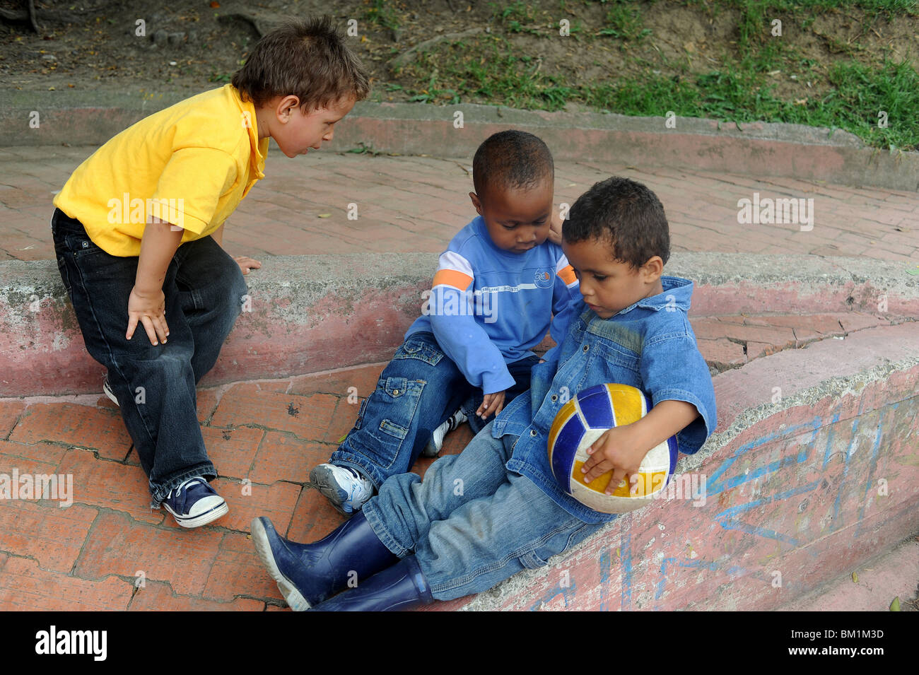 3 boys 3-4 years playing in park in Medellin. Stock Photo