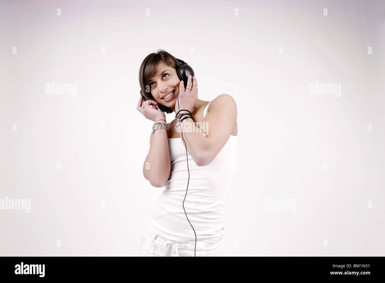 Young brunette woman, 25 years, standing, wearing headphones, listening to music, vibrant, joyful Stock Photo