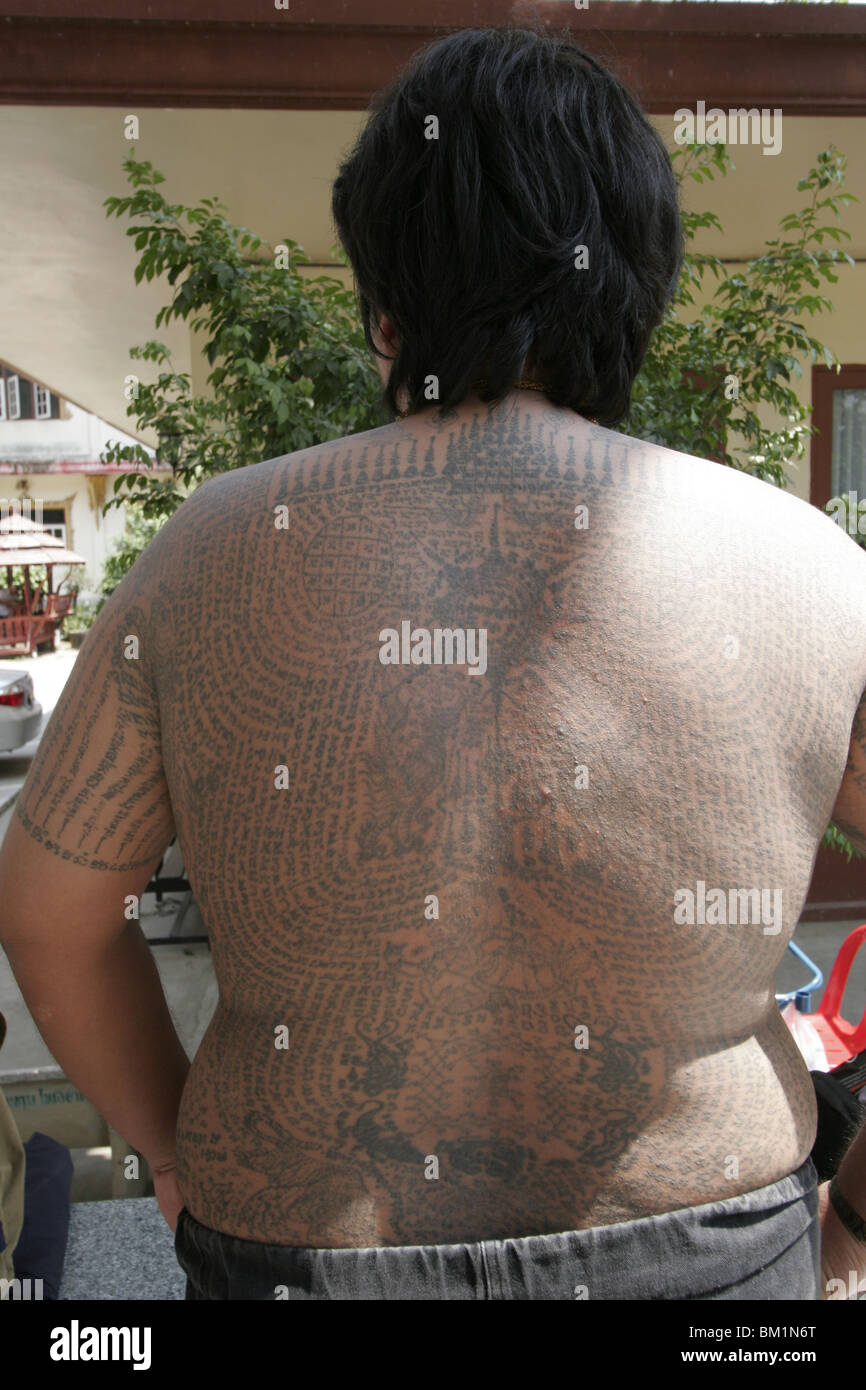 A fat young man shows off his tattoos during Wai Kru Day at Wat Bang Phra, a Thai temple where monks tattoo their devotees. Stock Photo