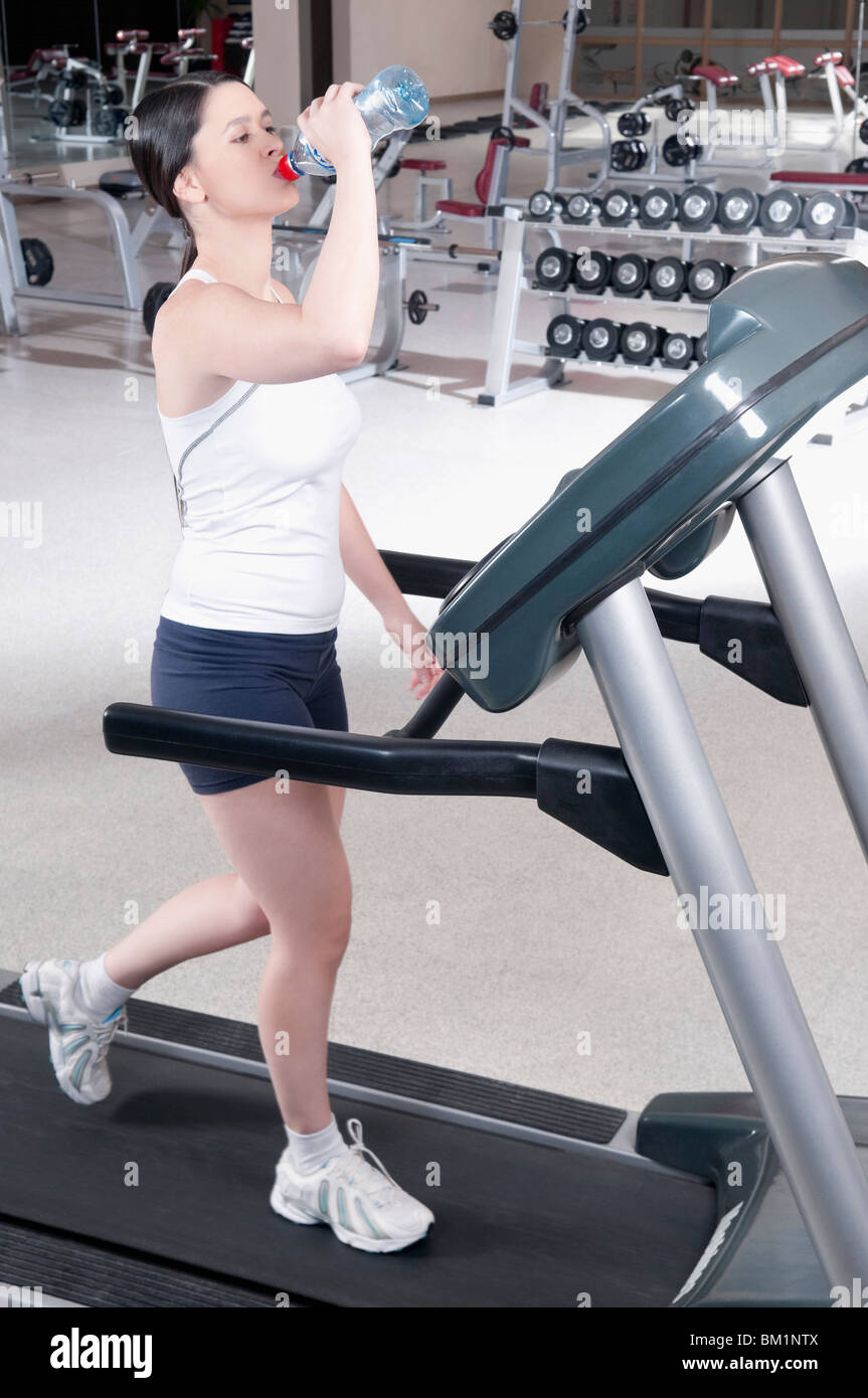 Woman drinking water on a treadmill Stock Photo Alamy
