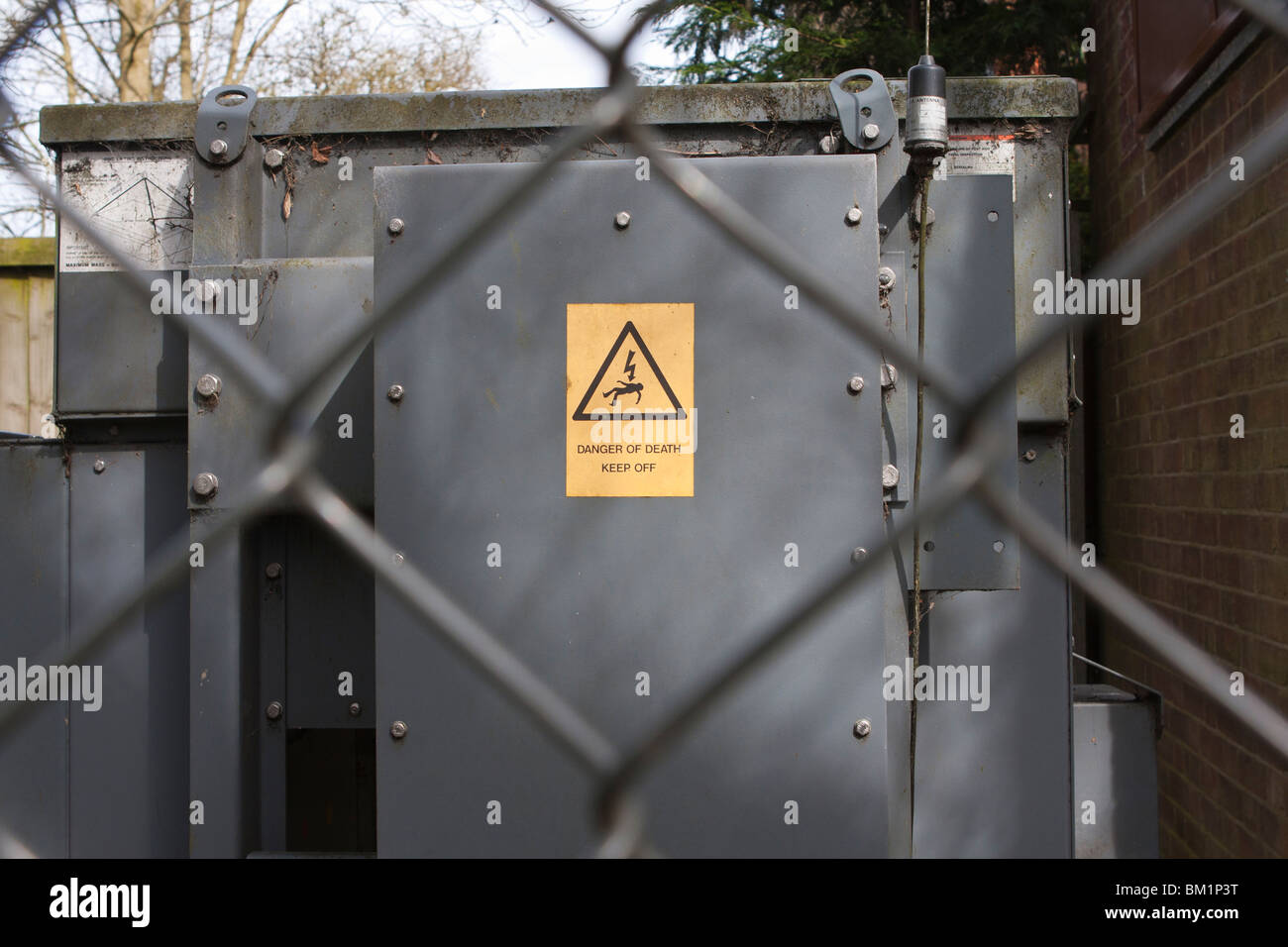 Warning sign on electricity substation behind chainlink fence Stock Photo