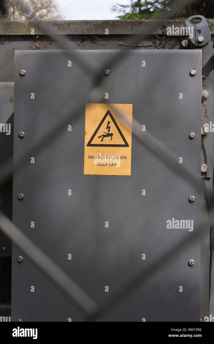 Warning sign on electricity substation behind chainlink fence Stock Photo