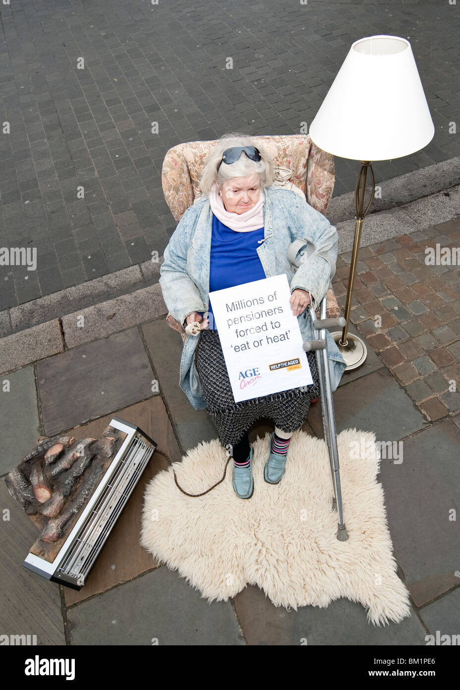 An elderly woman sits in a mock living room in front of the Palace of Westminster Stock Photo