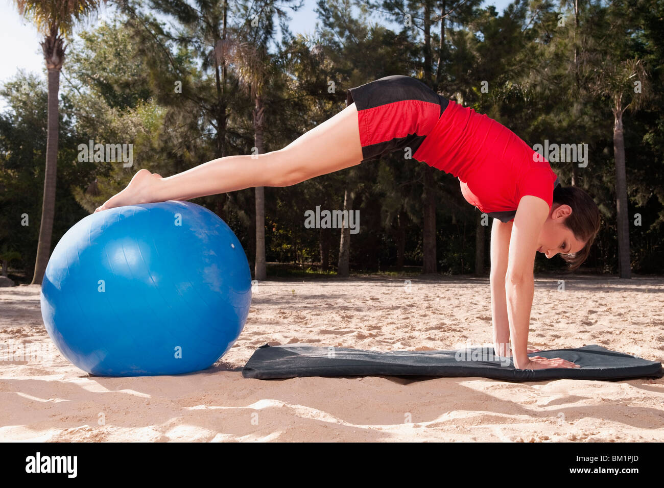 Woman exercising with a fitness ball on the beach Stock Photo
