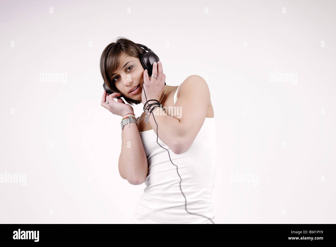 Young brunette woman, 25 years, standing, wearing headphones, listening to music, vibrant, joyful Stock Photo