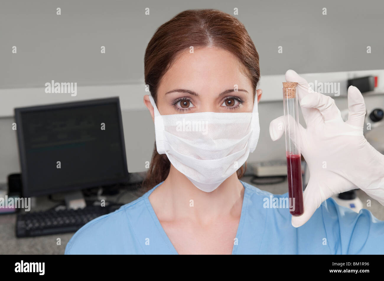 Female lab technician analyzing a blood sample in a test tube Stock Photo