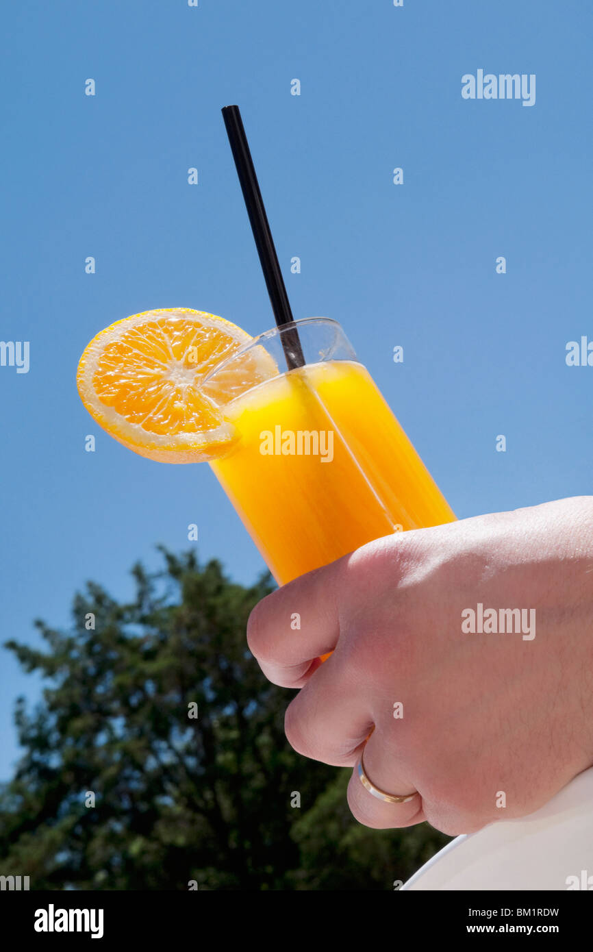 Person's hand holding a glass of orange juice Stock Photo