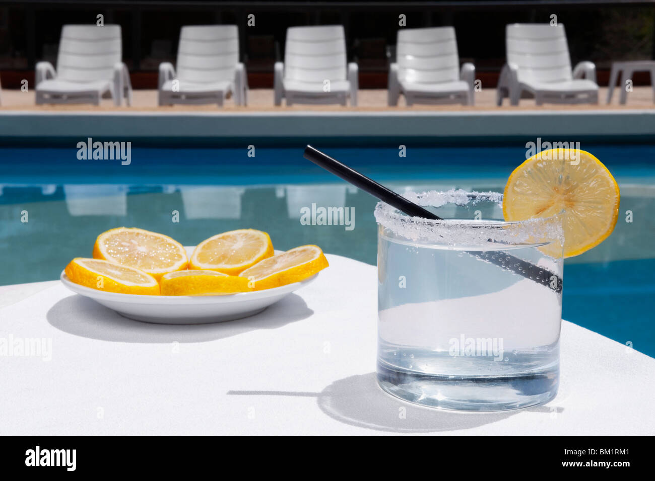 Glass of lemonade with lemon slices at the poolside Stock Photo