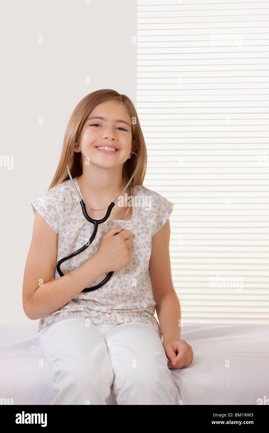 Portrait of a girl listening her heartbeat with a stethoscope Stock Photo