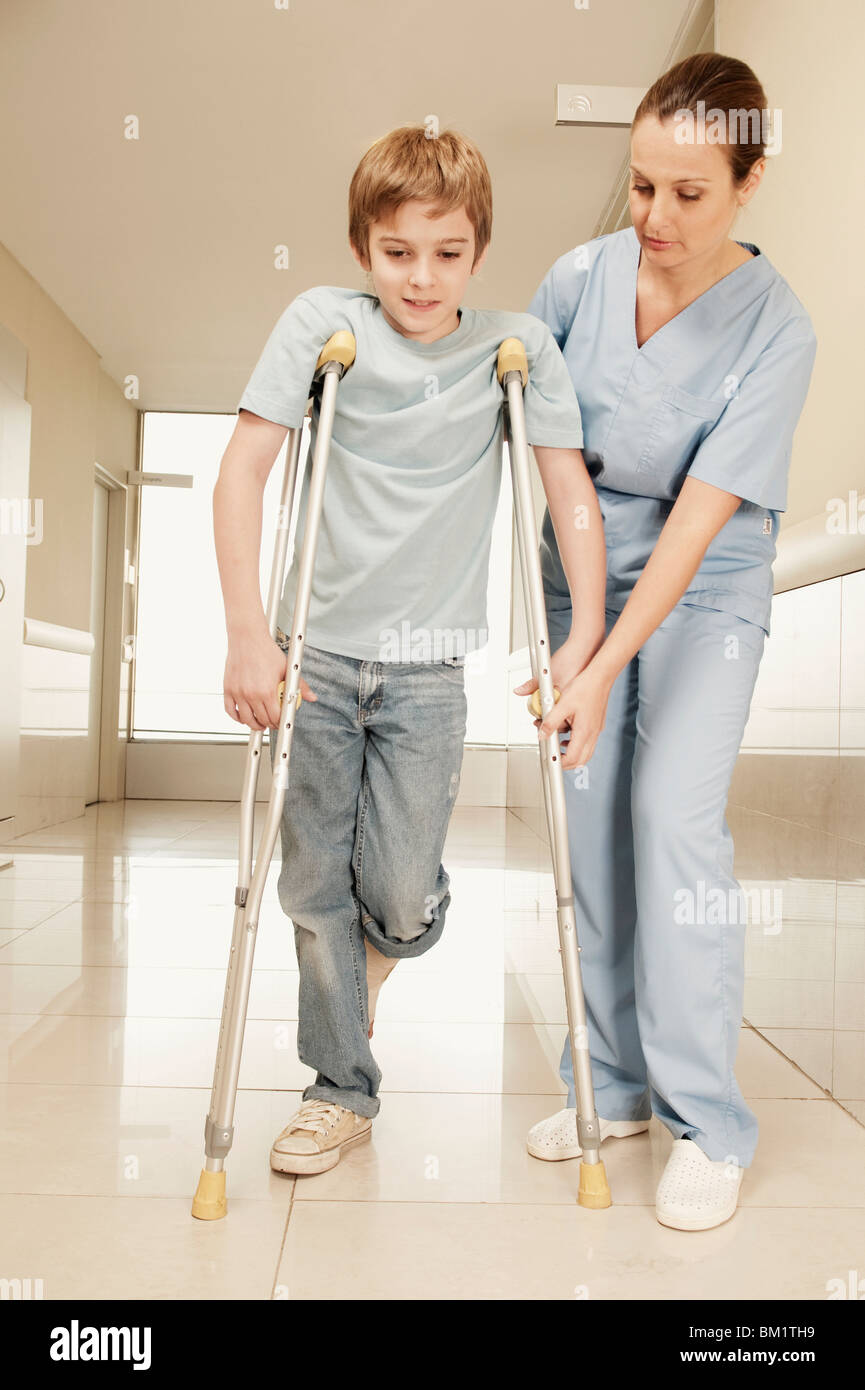 Female nurse assisting a boy on crutches Stock Photo Alamy