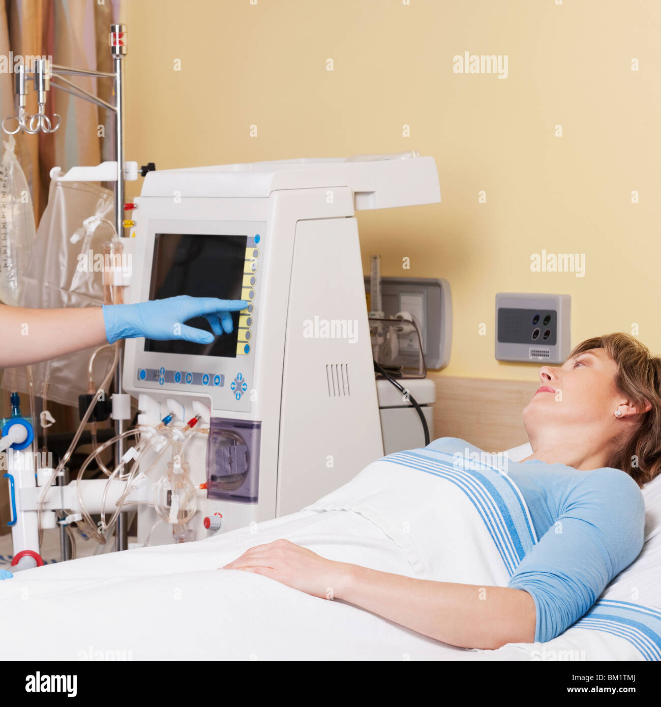 Female patient lying on the bed with a doctor working on a cardiac monitor Stock Photo