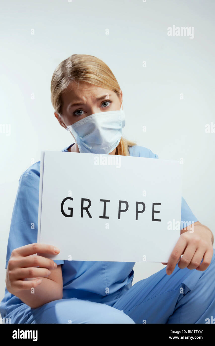 Portrait of a female surgeon showing a placard with word GRIPPE written on it Stock Photo