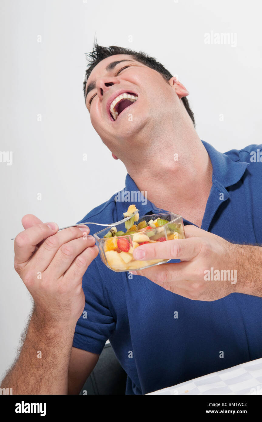 Man laughing while eating fruit salad Stock Photo Alamy