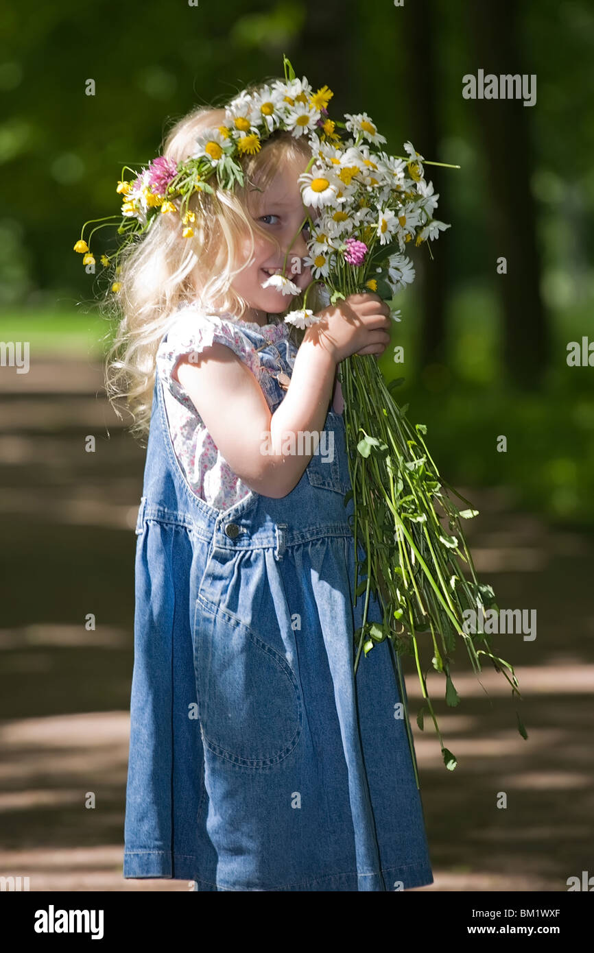 small smiling girl in a wreath is hidden a bunch of flowers Stock Photo ...
