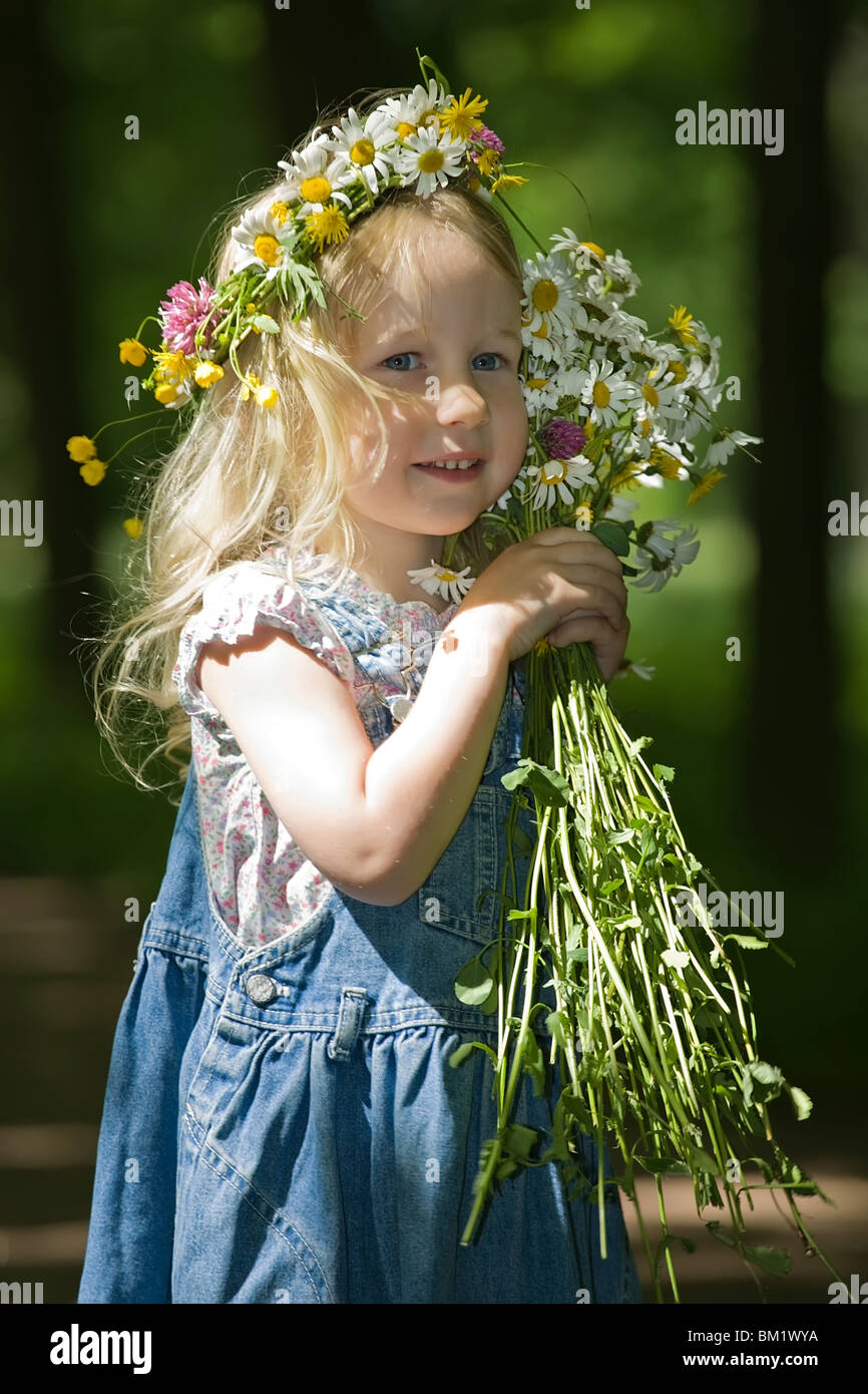 little smiling girl in a wreath and with a bouquet looks aside Stock ...