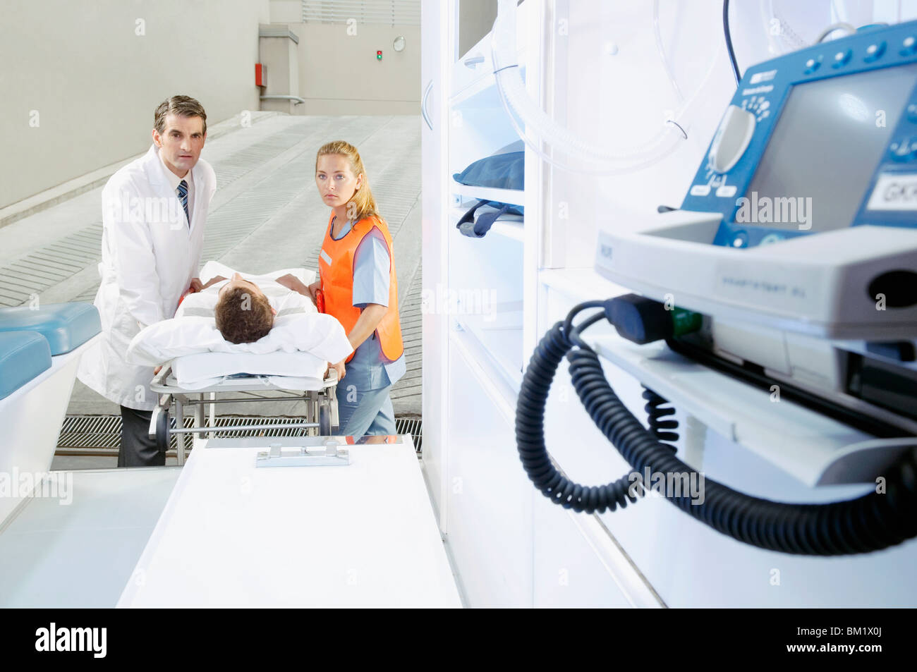 Paramedics pushing a patient on a gurney from an ambulance Stock Photo