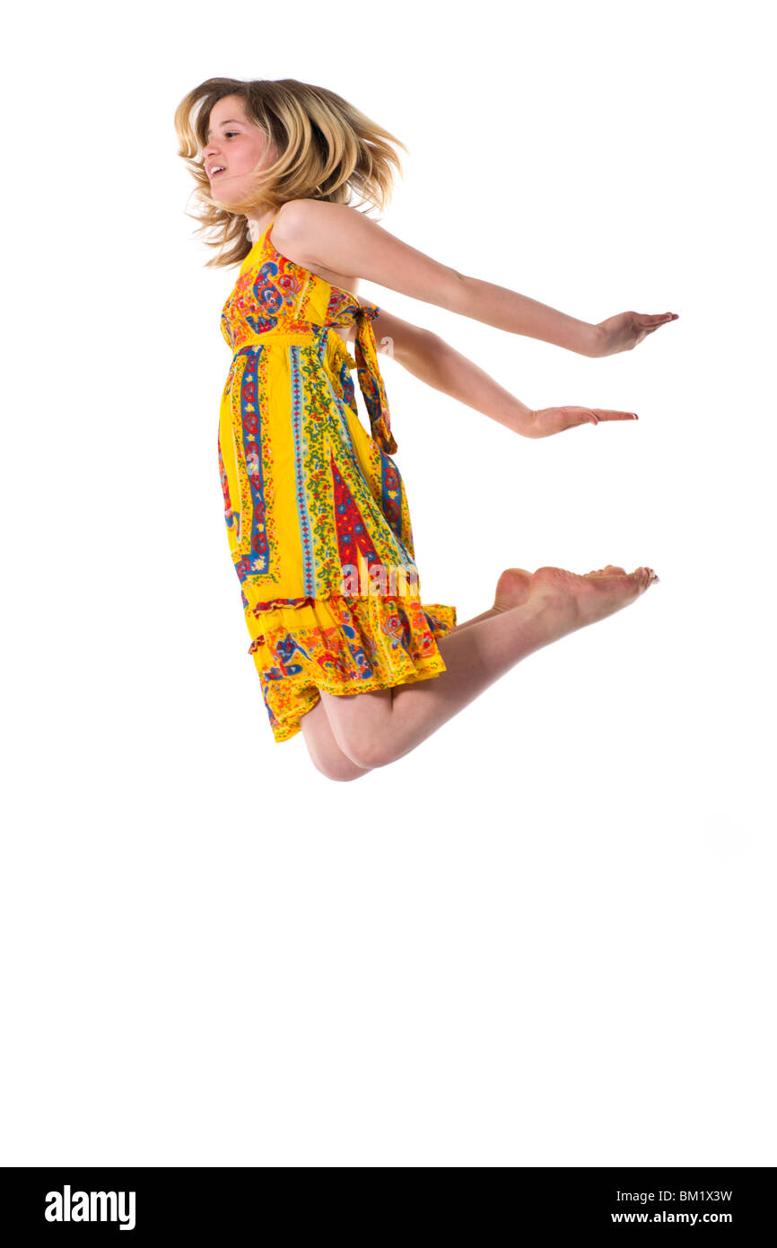 A young teenage girl in a colourful dress jumps in the air. Stock Photo