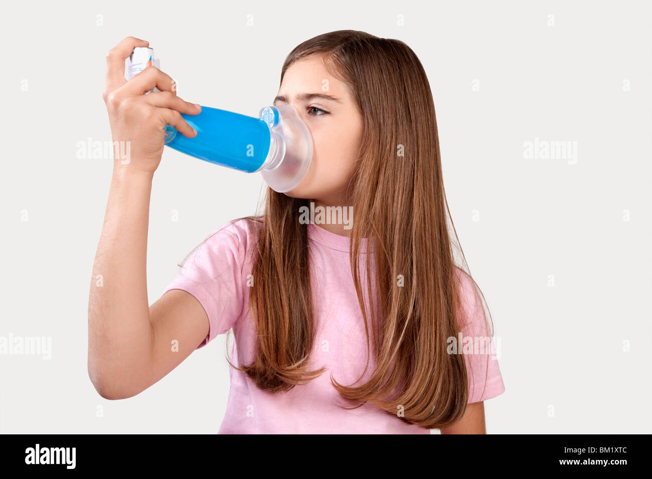 Girl using an asthma inhaler attached with spacer Stock Photo