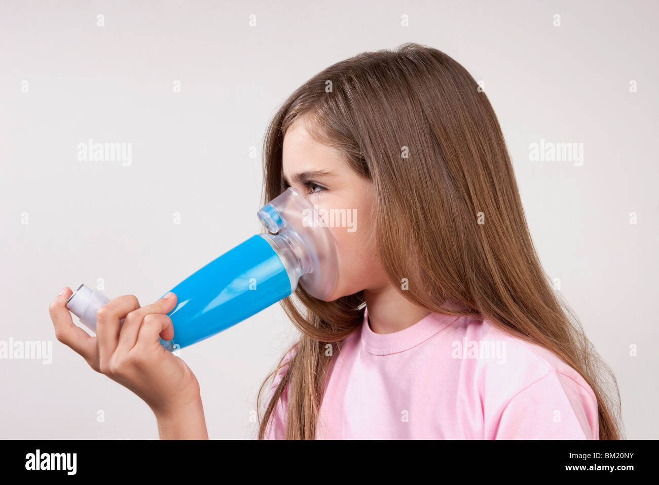 Girl using an asthma inhaler attached with a spacer Stock Photo