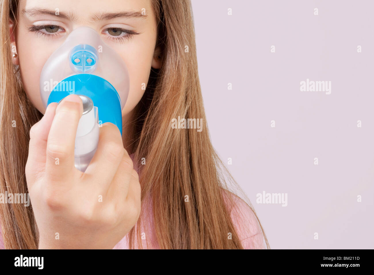 Girl using an asthma inhaler attached with spacer Stock Photo