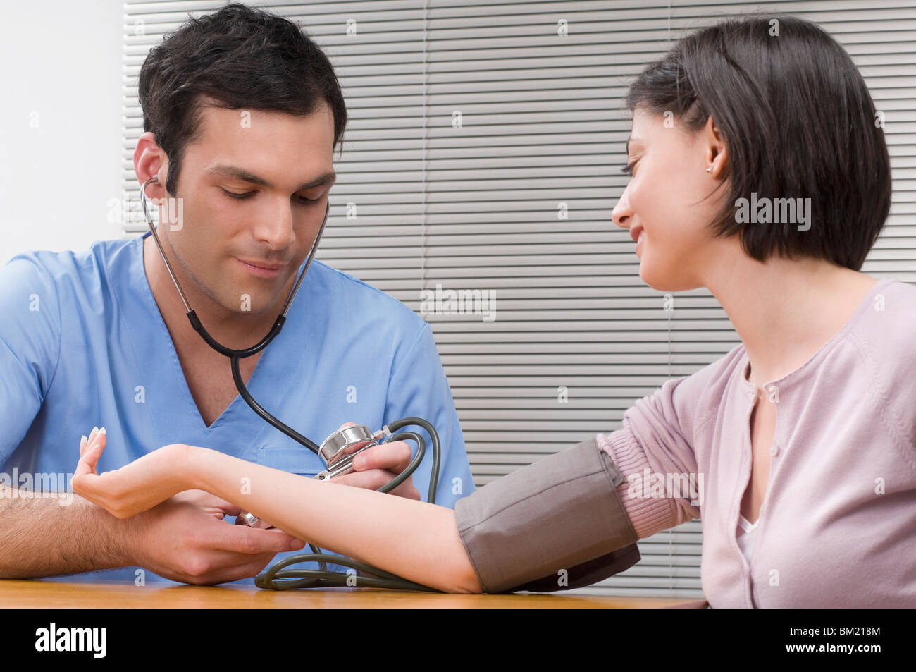 Doctor checking a woman's blood pressure Stock Photo - Alamy