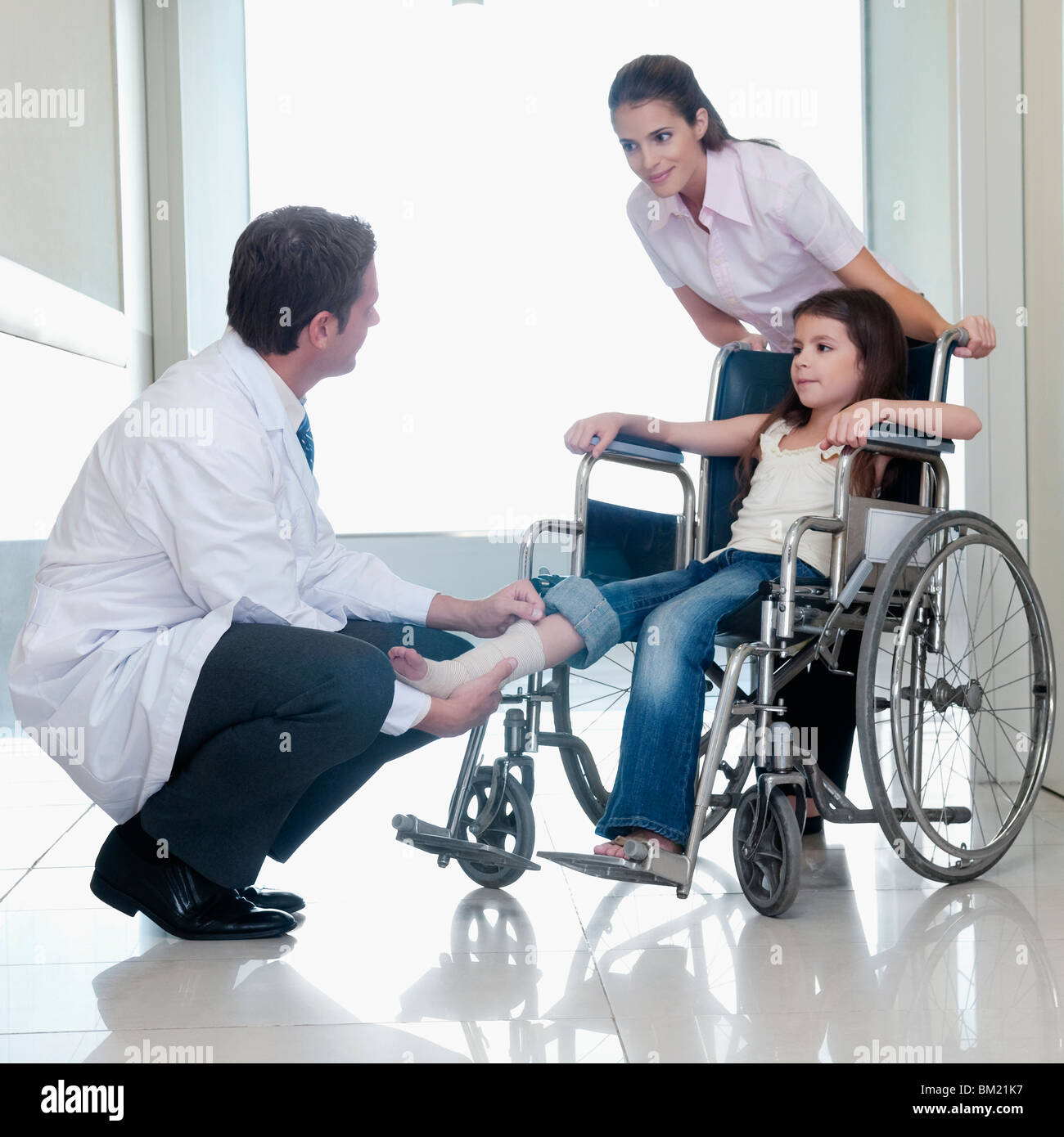 Two doctors with a patient sitting in a wheelchair Stock Photo Alamy