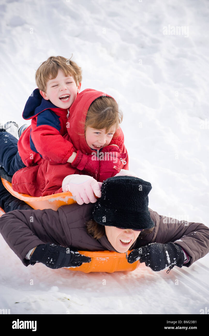 Mid adult woman tobogganing with her two children, Ithaca, New York