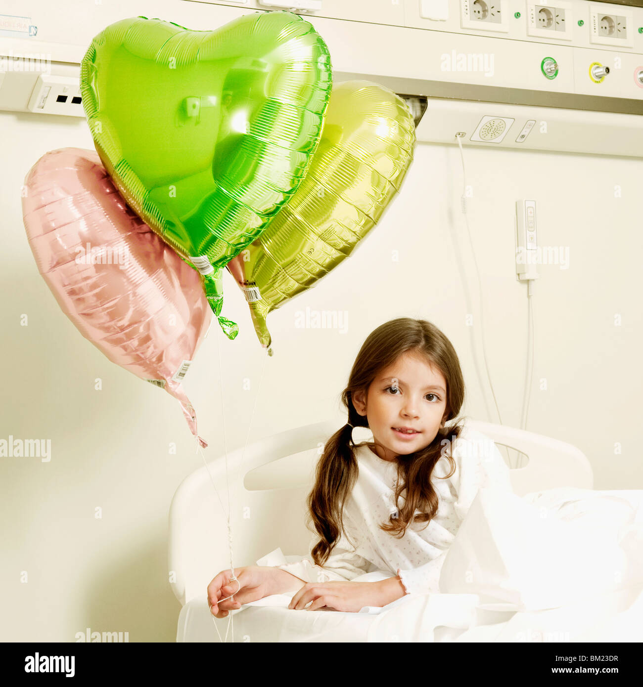 Girl with balloons on a hospital bed Stock Photo