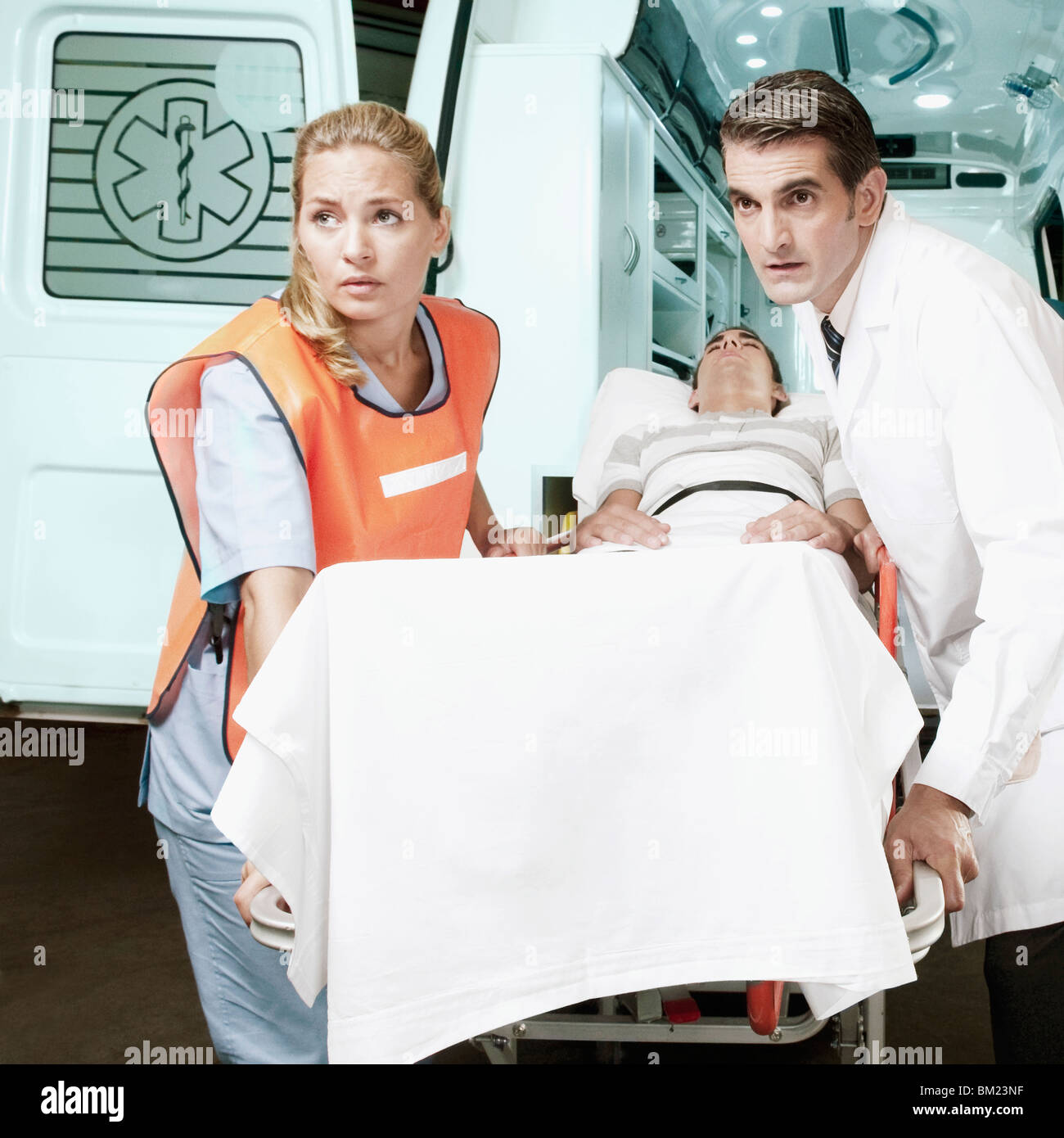 Paramedics pushing a patient on a gurney from an ambulance Stock Photo