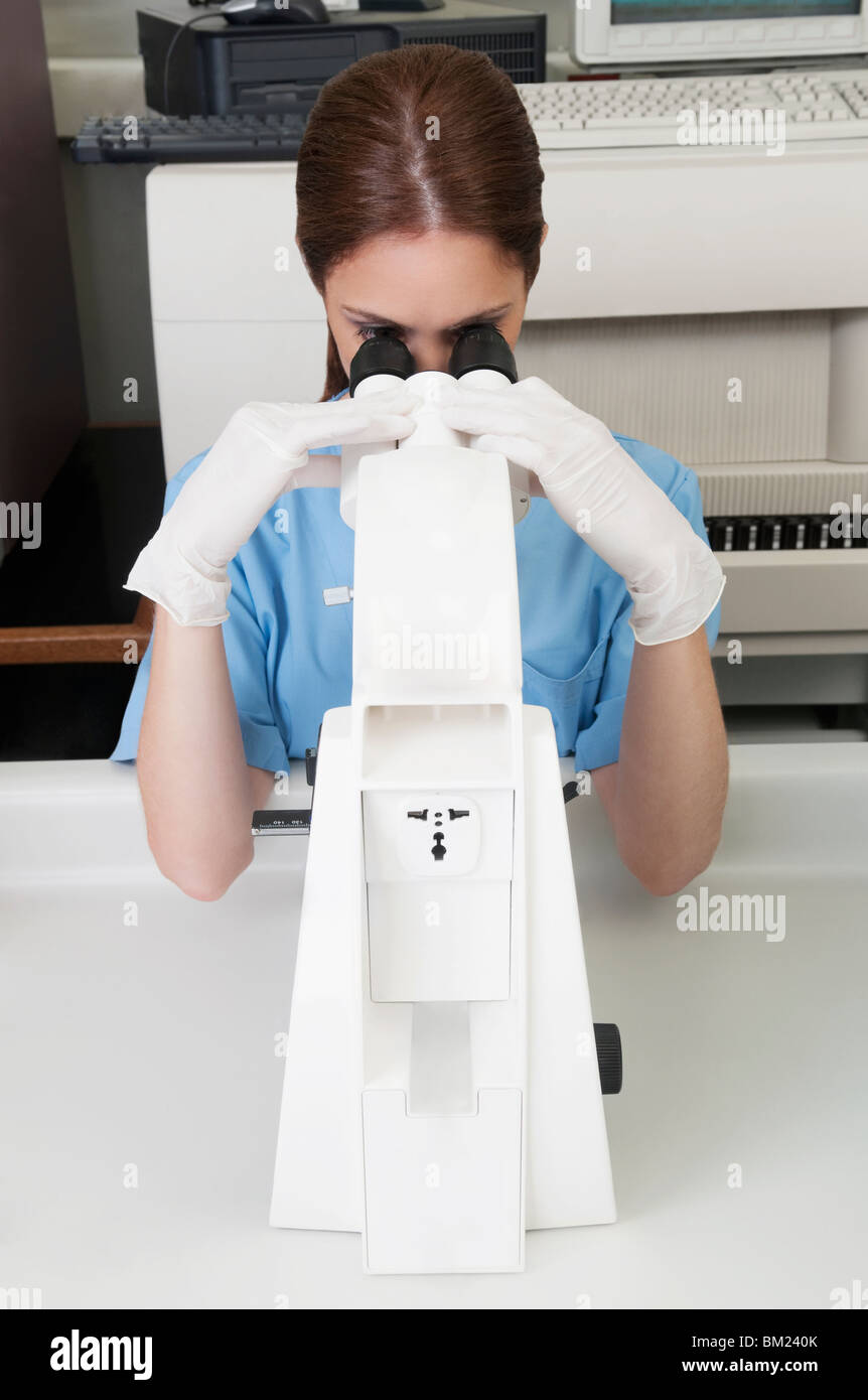 Female lab technician analyzing a sample through a microscope Stock ...