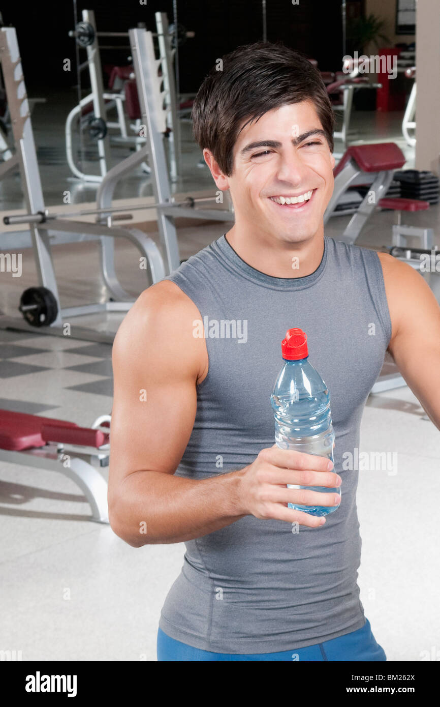 Man holding a water bottle and smiling in a gym Stock Photo - Alamy