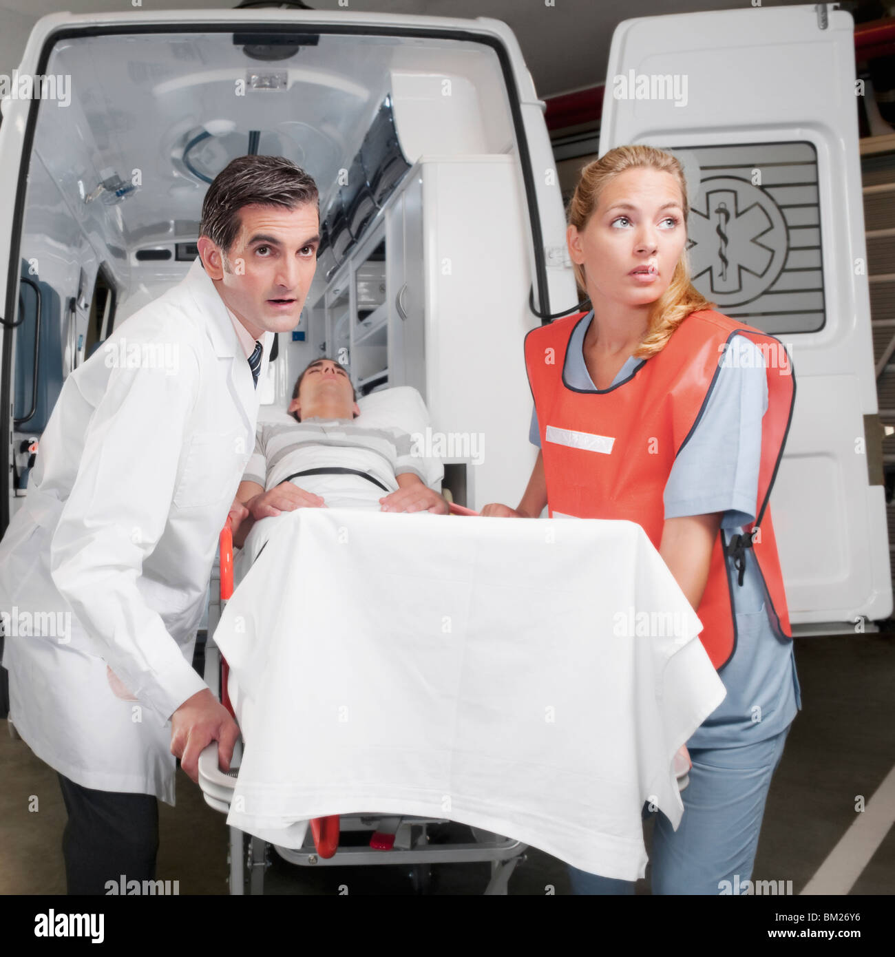 Paramedics leading a patient on a gurney from an ambulance Stock Photo