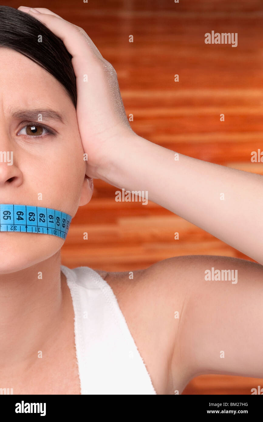 Woman covering her mouth with a tape measure Stock Photo