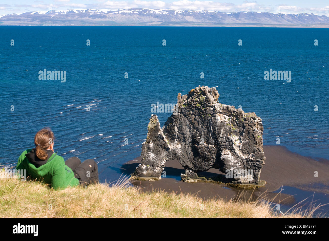 Tourist relaxing at the famous Hvitserkur rock formation, Vatnsnes Peninsula, Iceland, Polar Regions Stock Photo