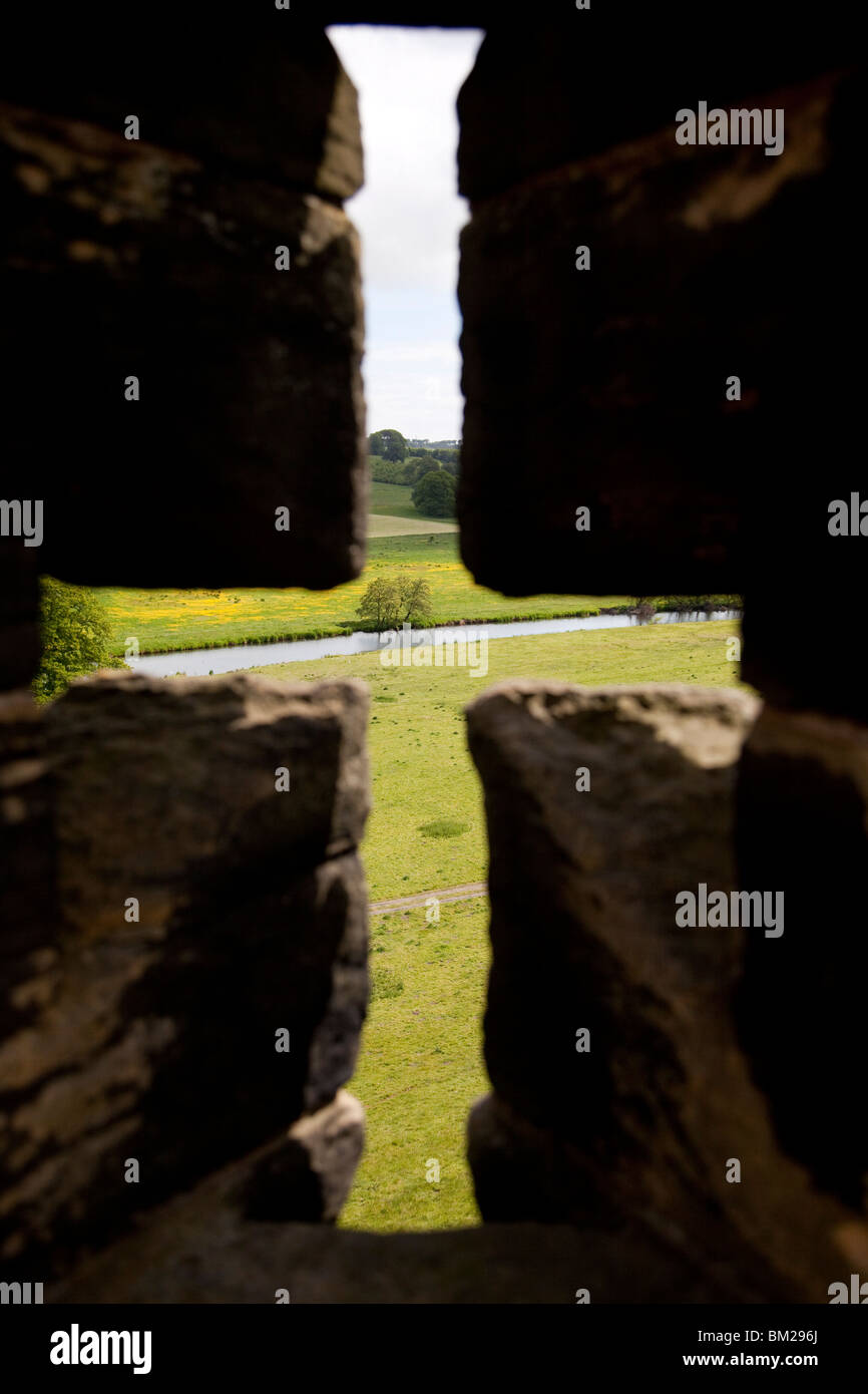 River Aln seen through arrow slit of the walls of Alnwick Castle, Northumberland, UK Stock Photo