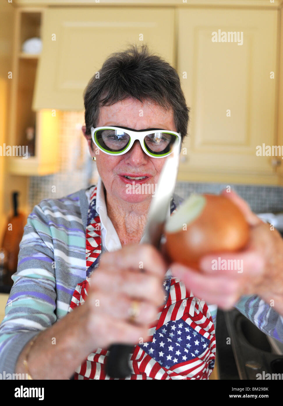 Woman preparing and peeling onions wearing special glasses to stop eyes