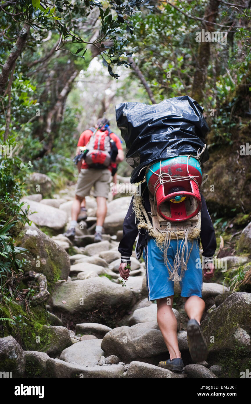 Porter and hiker on trail, Kinabalu National Park, Sabah, Borneo, Malaysia, Southeast Asia Stock Photo