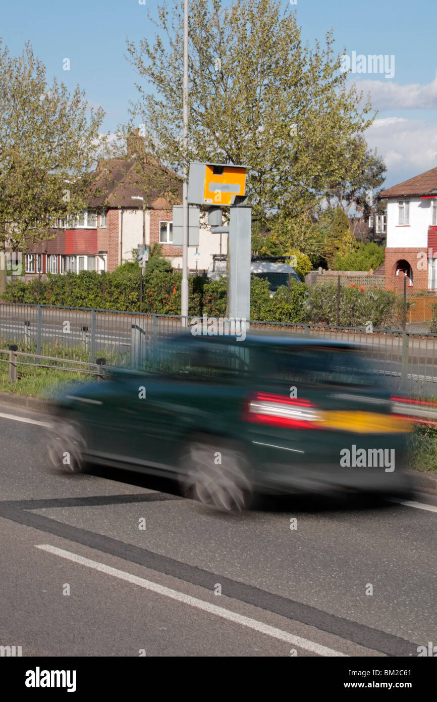 A dark green car speeding past a Gatso speed camera on the A316 Great Chertsey Road, Hounslow, UK. SEE DESCRIPTION Stock Photo