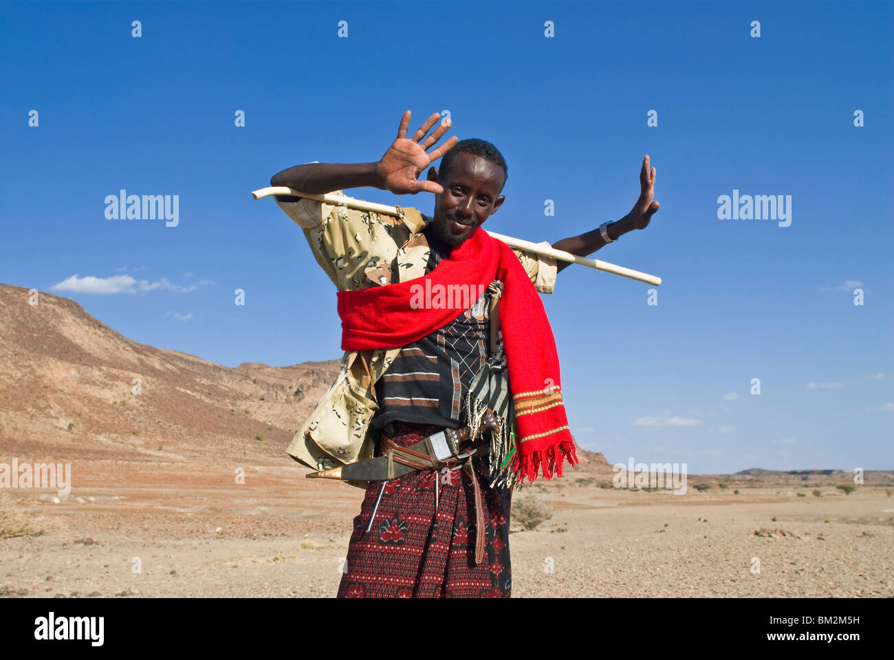 A young native man grinnig cheekily and holding a stick, Lac Abbe, Djibouti Stock Photo