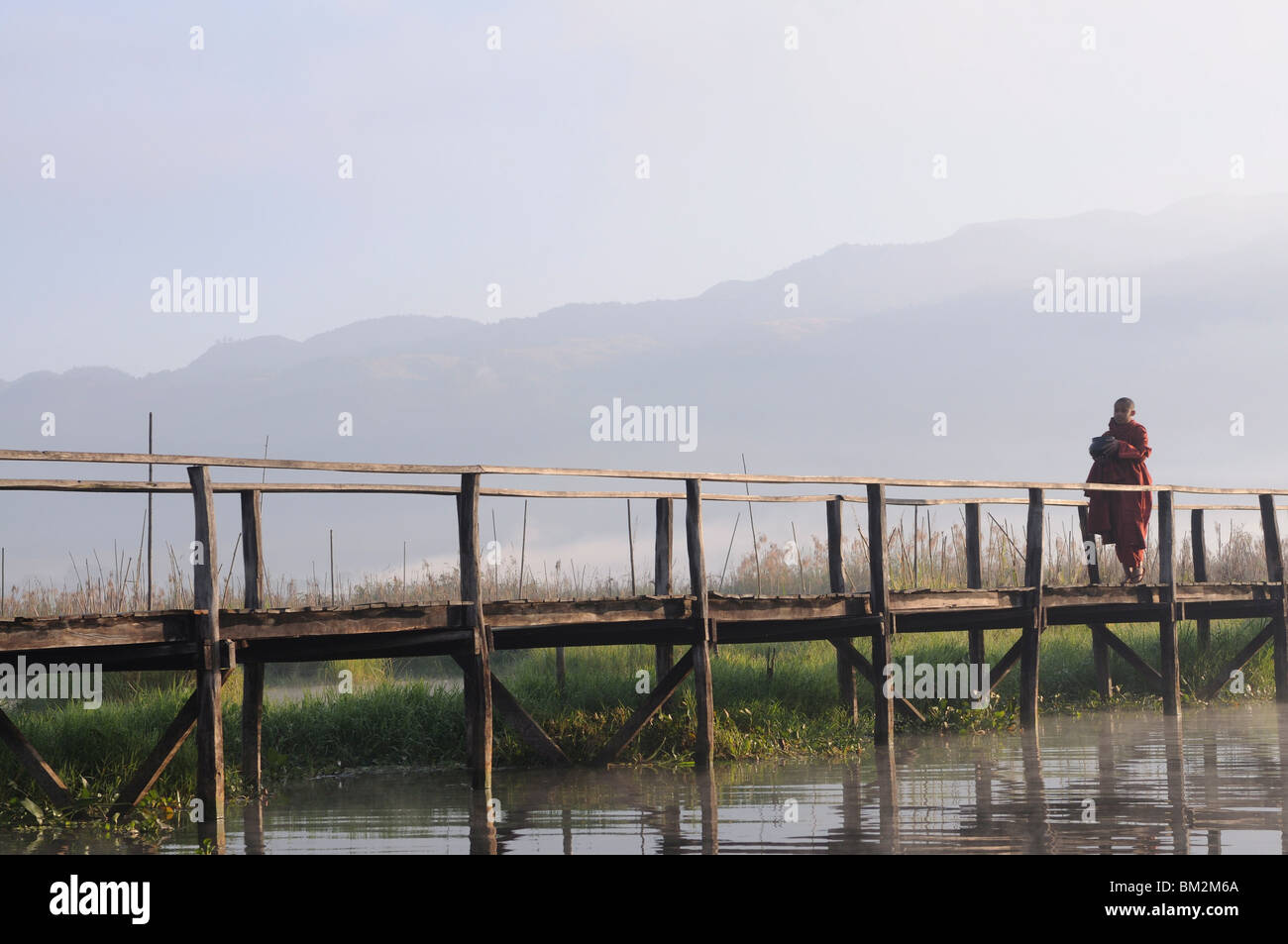 Buddhist monk, walking in the early morning on a wooden walkway, Inle Lake, Myanmar (Burma) Stock Photo