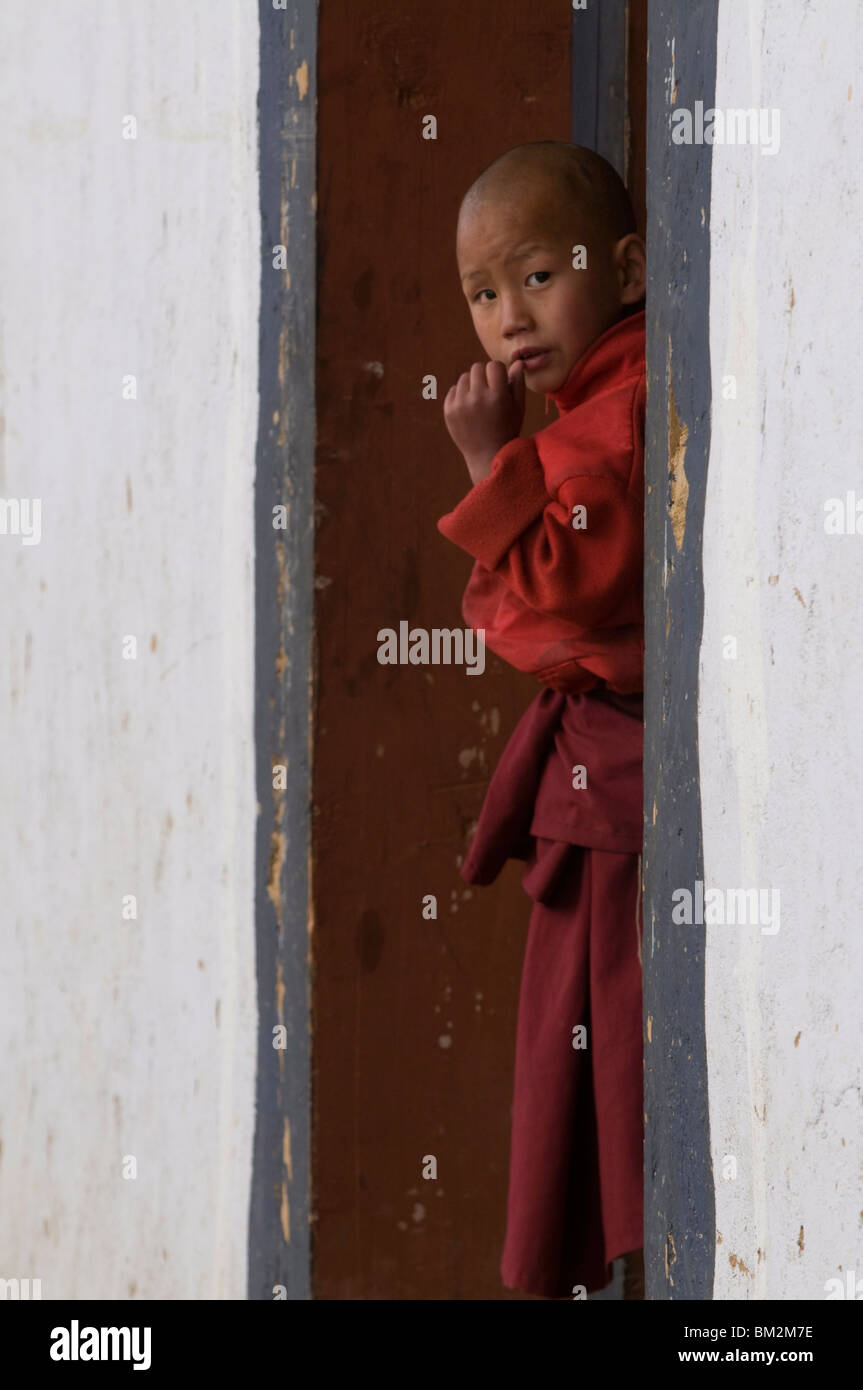 Little monk curiously looking around the corner in the Gangte Goempa, Bhutan Stock Photo