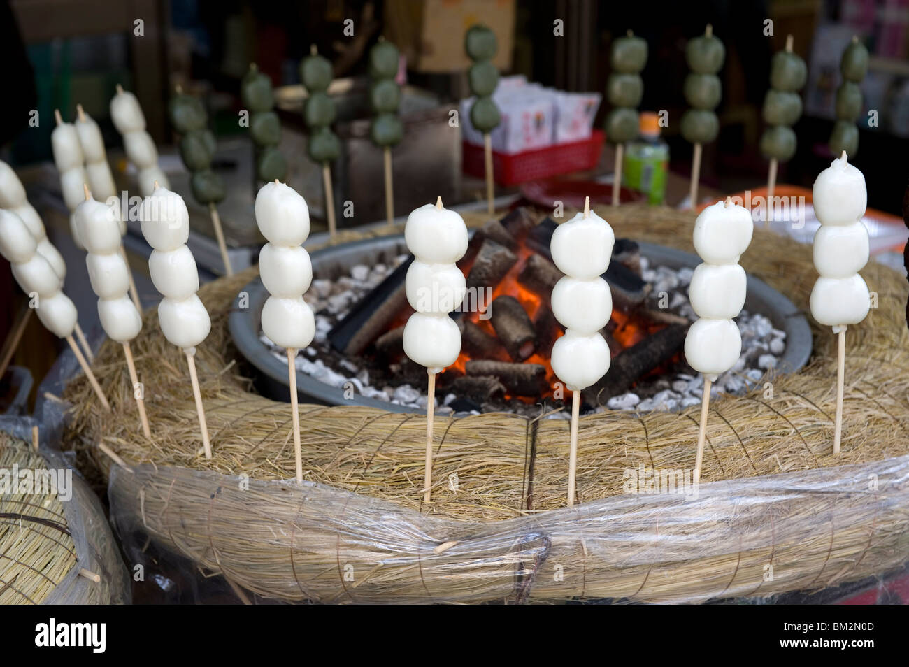 Japanese snack called dango (three sticky rice cake balls on a skewer) warming beside hot coals, Japan Stock Photo