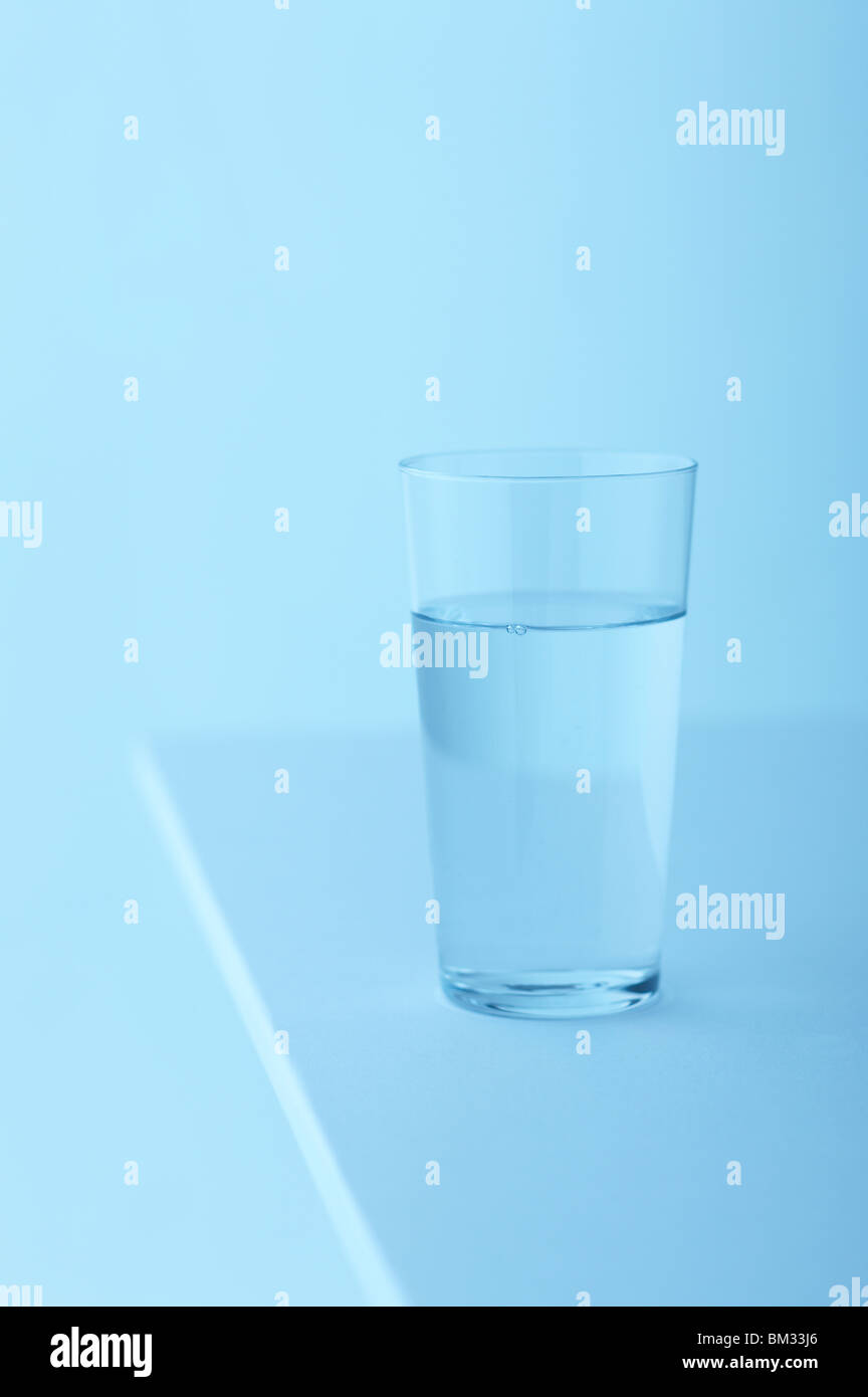 Glass of water on table, blue background, soft focus Stock Photo Alamy