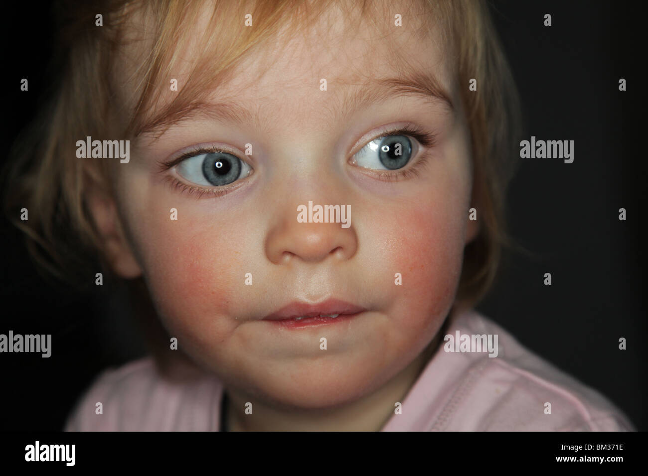 GIRL BABY TODDLER THINKING BIG EYES: One year old baby girl thinking bites biting her lip thoughtful model released taken with ring flash Stock Photo