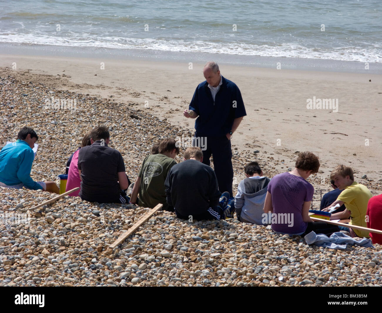 Students class outdoor lesson on beach with tutor, Southbourne, Bournemouth, Dorset, UK Stock Photo