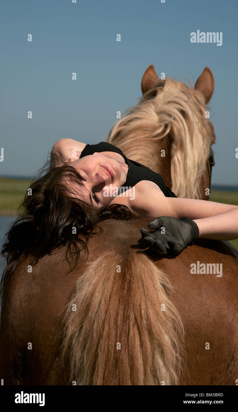 Horsewoman on a brown horse walk on a wild meadow Stock Photo